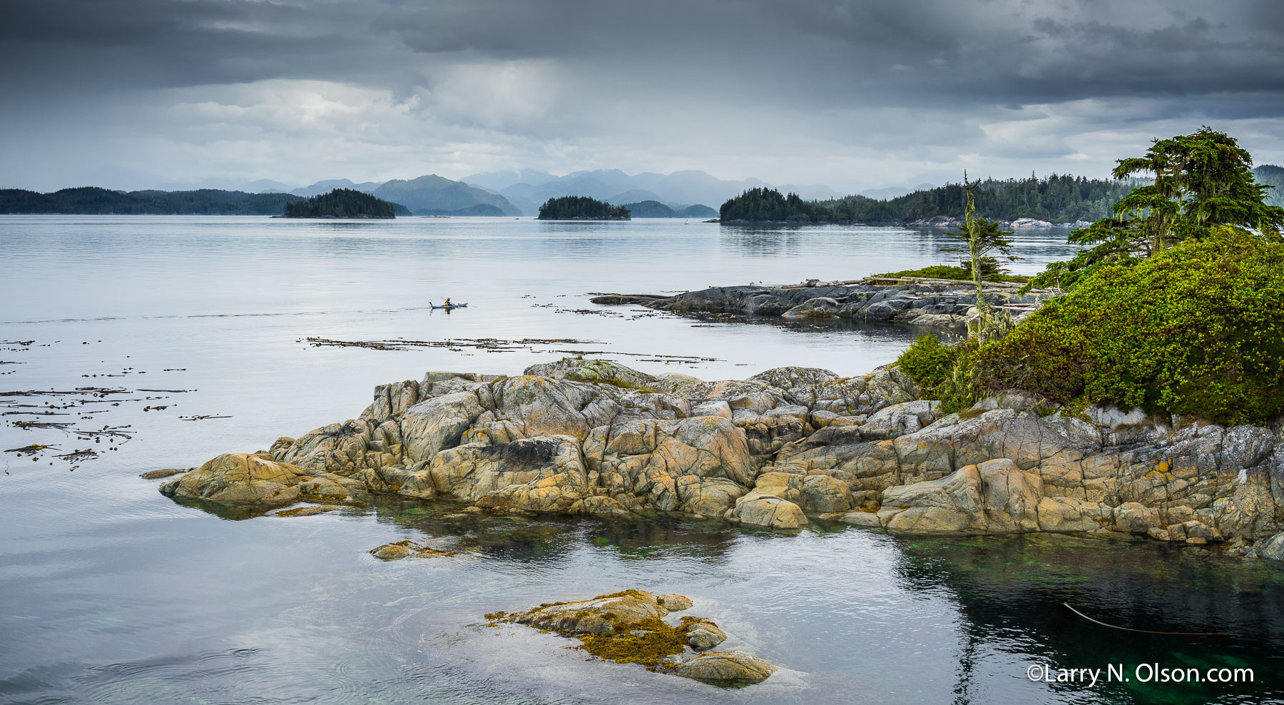 Solo Kayaker, Broughton Archipelago, BC, | Solo Kayaker paddles through the glassy waters of the Broughton Archipelago, BC.