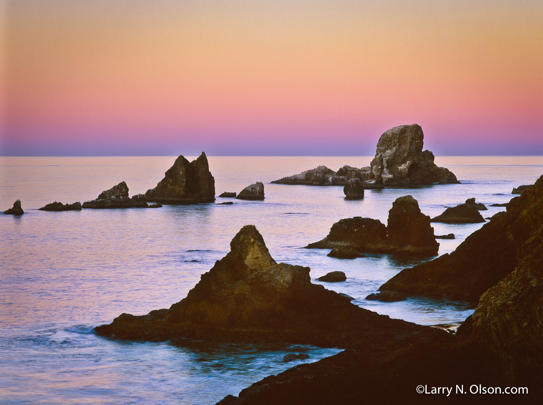 Ecola Point Rocks, Oregon Islands National Wildlife Refuge,  OR | The pink of dawn is reflected upon an extremely calm ocean with sea stacks, home to thousands of shore birds and marine mammals.